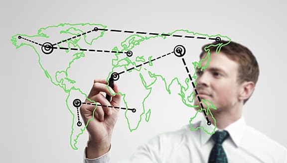 Ejecutivo dibujando conexiones entre continentes sobre un mapa del mundo